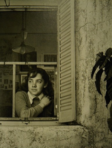 Se ve a una joven María Elena Walsh asomando a una ventana. Foto en blanco y negro.