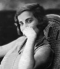 Retrato en blanco y negro de Silvina Ocampo joven, sentada en un sillón de mimbre. Apoya la mano sobre el rostro y mira hacia la cámara con gesto pensativo. Lleva un vestido claro sin mangas y un collar de perlas.