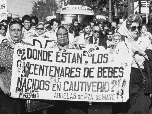 Fotografía de una marcha. En primer plano un cartel en el que se lee: ¿Dónde están los centenares de bebes nacidos en cautiverio.