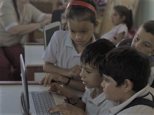 Chicas y chicos frente a una netbook en el aula.