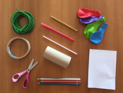 Sobre una superficie se ven globos, lápices, hilos, tijera y papel.