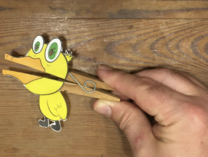 Mano presionando el broche para que el títere del pato abra la boca.