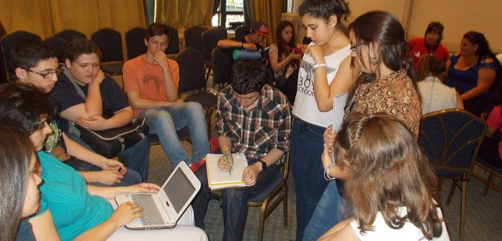 Jóvenes sentados en círculo con netbooks sobre las piernas en una capacitación. 