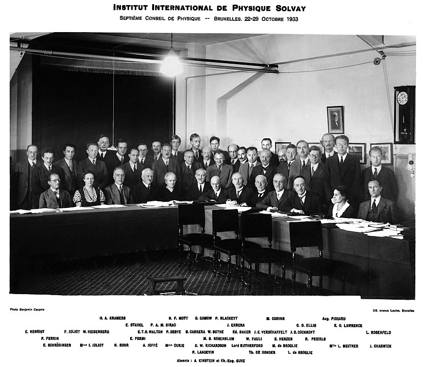 De pie y sentados, participantes del Congreso Solvay de 1933. Entre muchos hombres de traje, hay tres mujeres. Foto en blanco y negro.