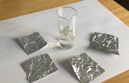  Vaso junto a papeles de aluminio recortados para formar las pelotitas.