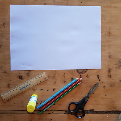 Papel blanco, una tijera,lápices de colores, una regla y un adhesivo vinílico dispuestos sobre una mesa.