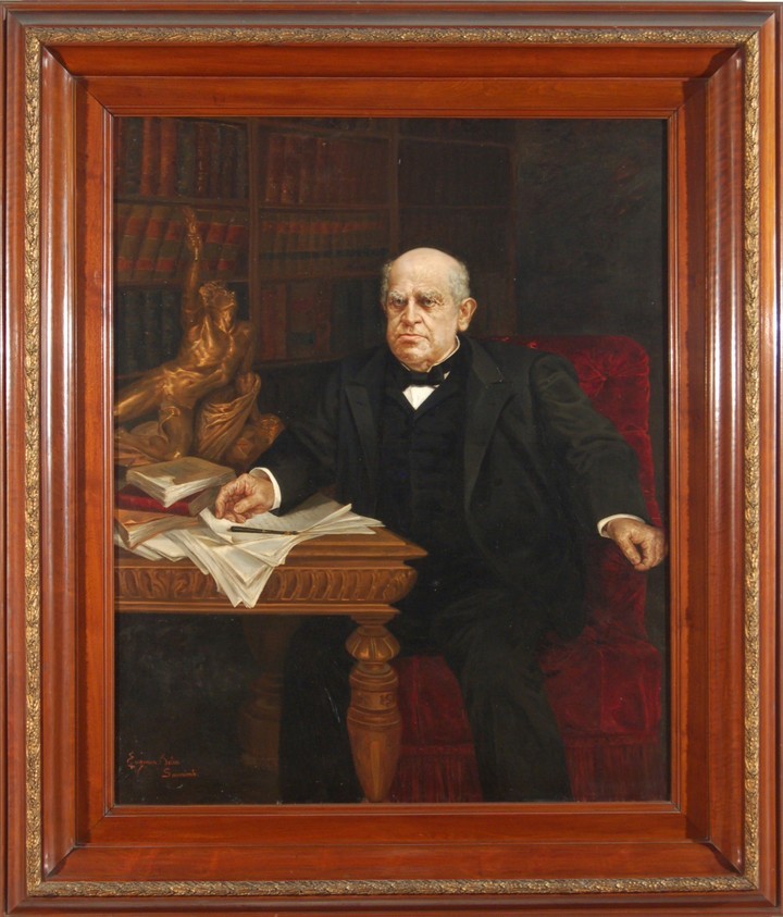 Retrato de Sarmiento. Está sentado, de traje, y se apoya en un escritorio lleno de papeles.