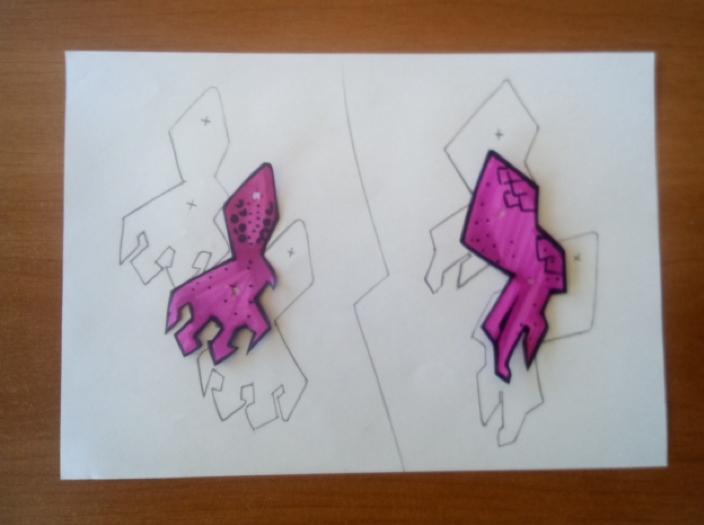 Una hoja con las patas del dragón dibujadas. Encima de la hoja hay dos patas ya coloreadas y recortadas.