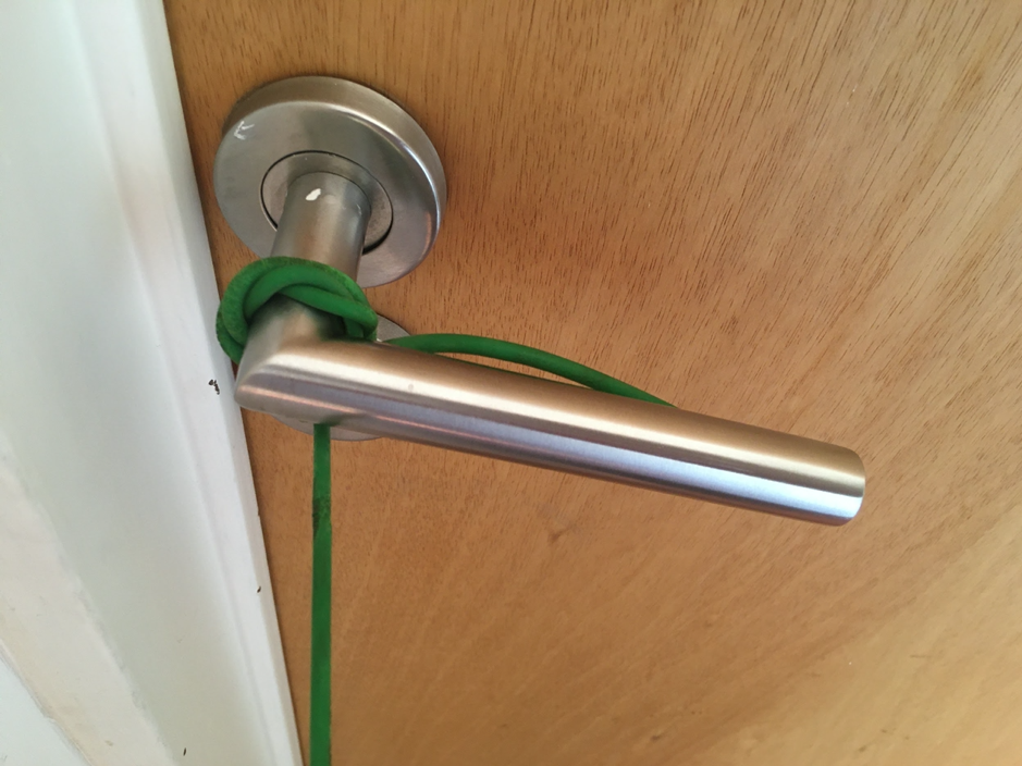 Soga sujeta al picaporte de una puerta cerrada.