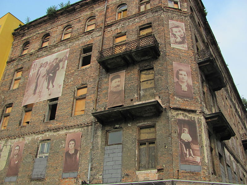 Fotografía de la esquina donde se encontraba el Gueto de Varsovia. Edificio antiguo de ladrillo se pueden ver fotografías gigantes en sus paredes con los protagonistas de la resistencia