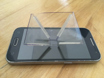 Pirámide apoyada con la base más chica sobre la pantalla de un teléfono celular. 