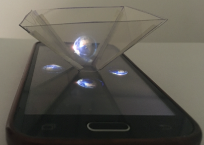 Teléfono celular reproduciendo un holograma 3D del planeta Tierra.