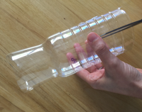 Una mano corta transversalmente el cuerpo de una botella.