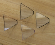 Cuatro recortes de plástico transparente con forma de trapecio.
