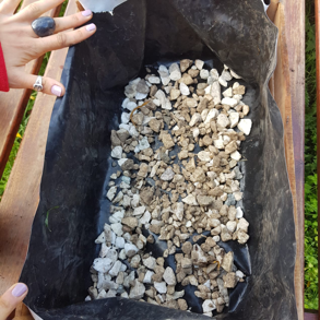 Cajón de madera con su interior cubierto por una bolsa, con piedras pequeñas distribuidas en todo su fondo.