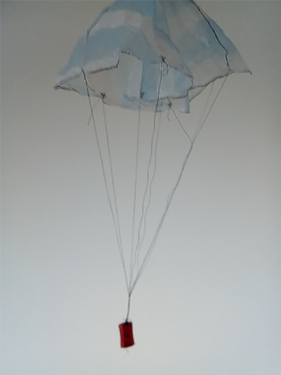 Paracaídas en descenso con el sacapuntas atado a sus hilos.