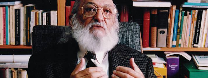 Fotografía de Paulo Freire con el fondo de una biblioteca.