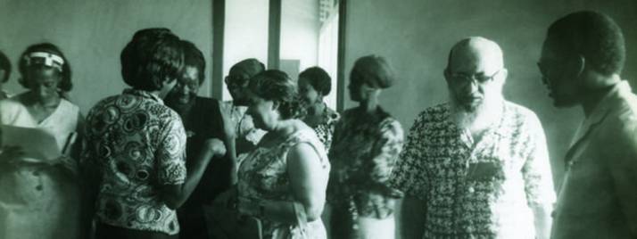 Fotografía de Paulo Freire en el Primer Seminario Nacional de Alfabetización de Santo Tomé y Príncipe, Brasil, 1976 rodeado de otras personas.