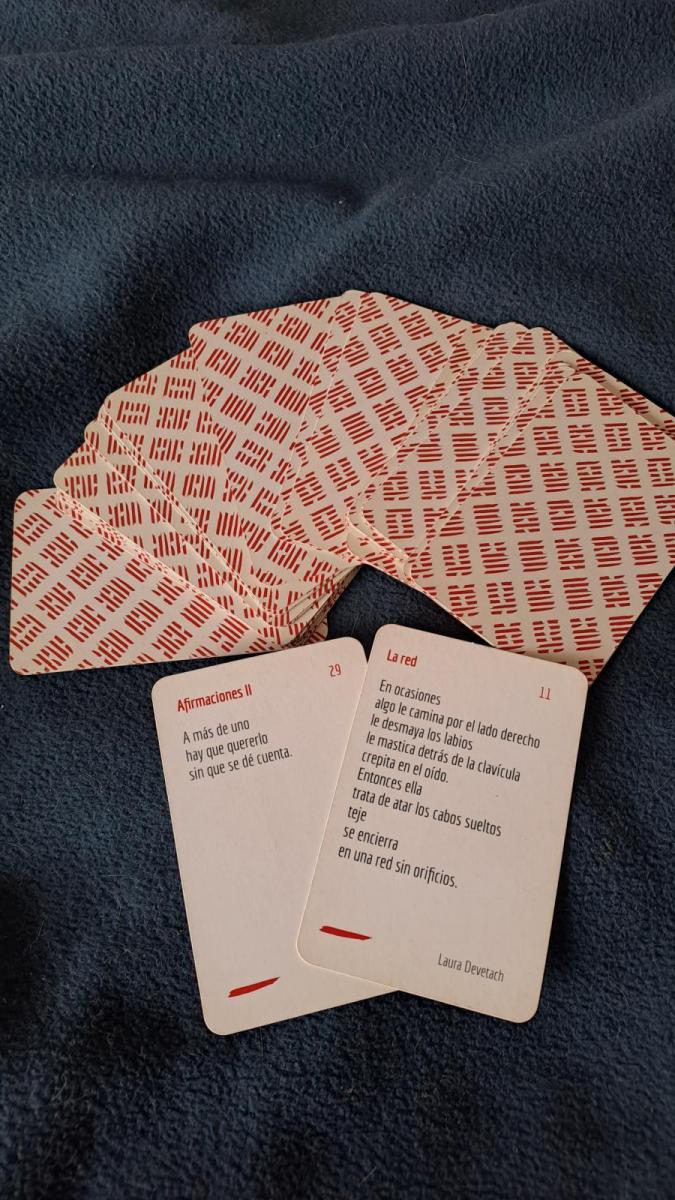 Mazo de cartas «Poesía a la carta» desplegado sobre una tela oscura. Cada carta tiene un poema breve.