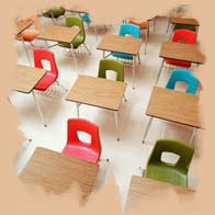 Varios pupitres en un aula con sillas de varios colores.