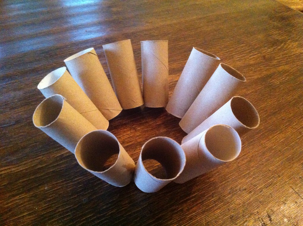 Once tubos de cartón obtenidos del papel higiénico que están apoyados en una mesa y ubicados en ronda, uno al lado del otro.