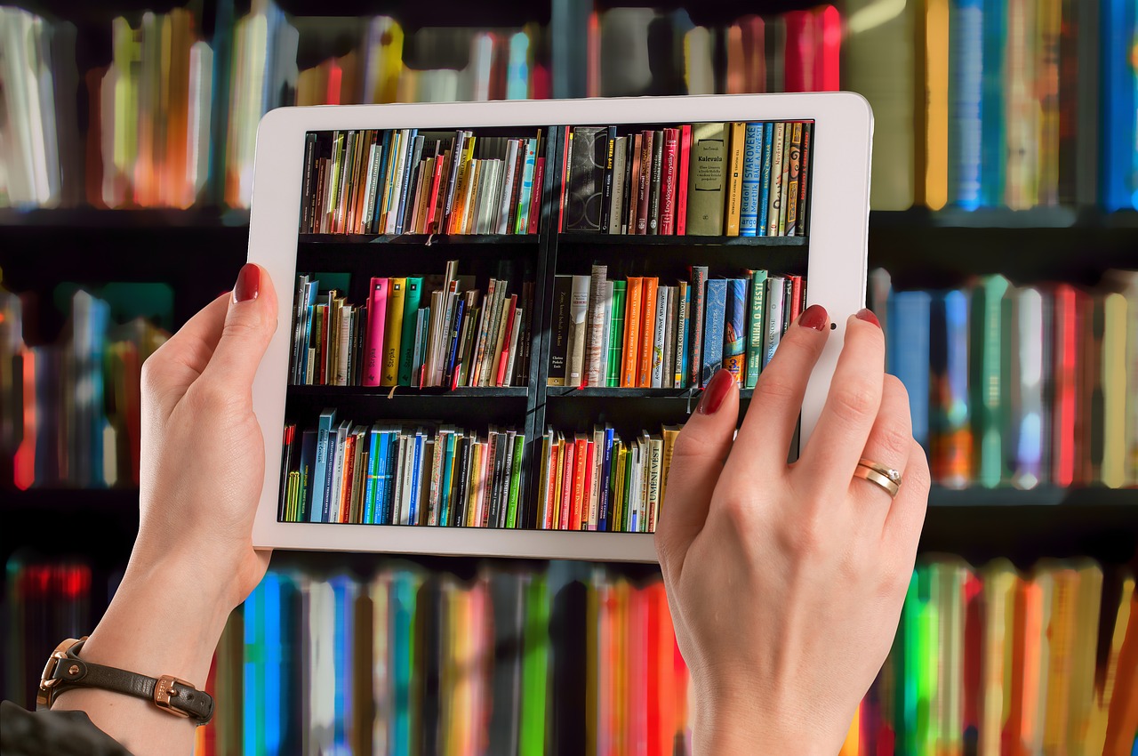 la imagen muestra una tablet sostenida por unas manos y dentro una imagen de libros.
