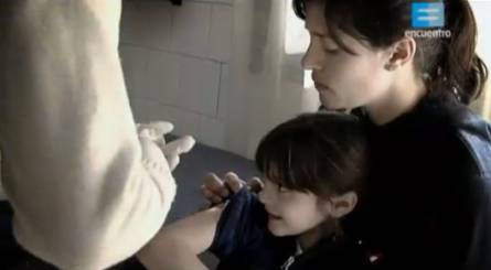 mujer con una niña en un consultorio médico, donde el doctor le aplica una vacuna a la niña.